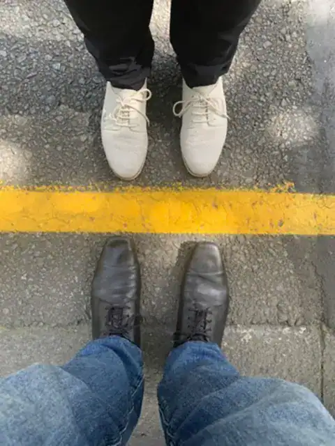 Two people standing on opposite sides of a painted line on the road